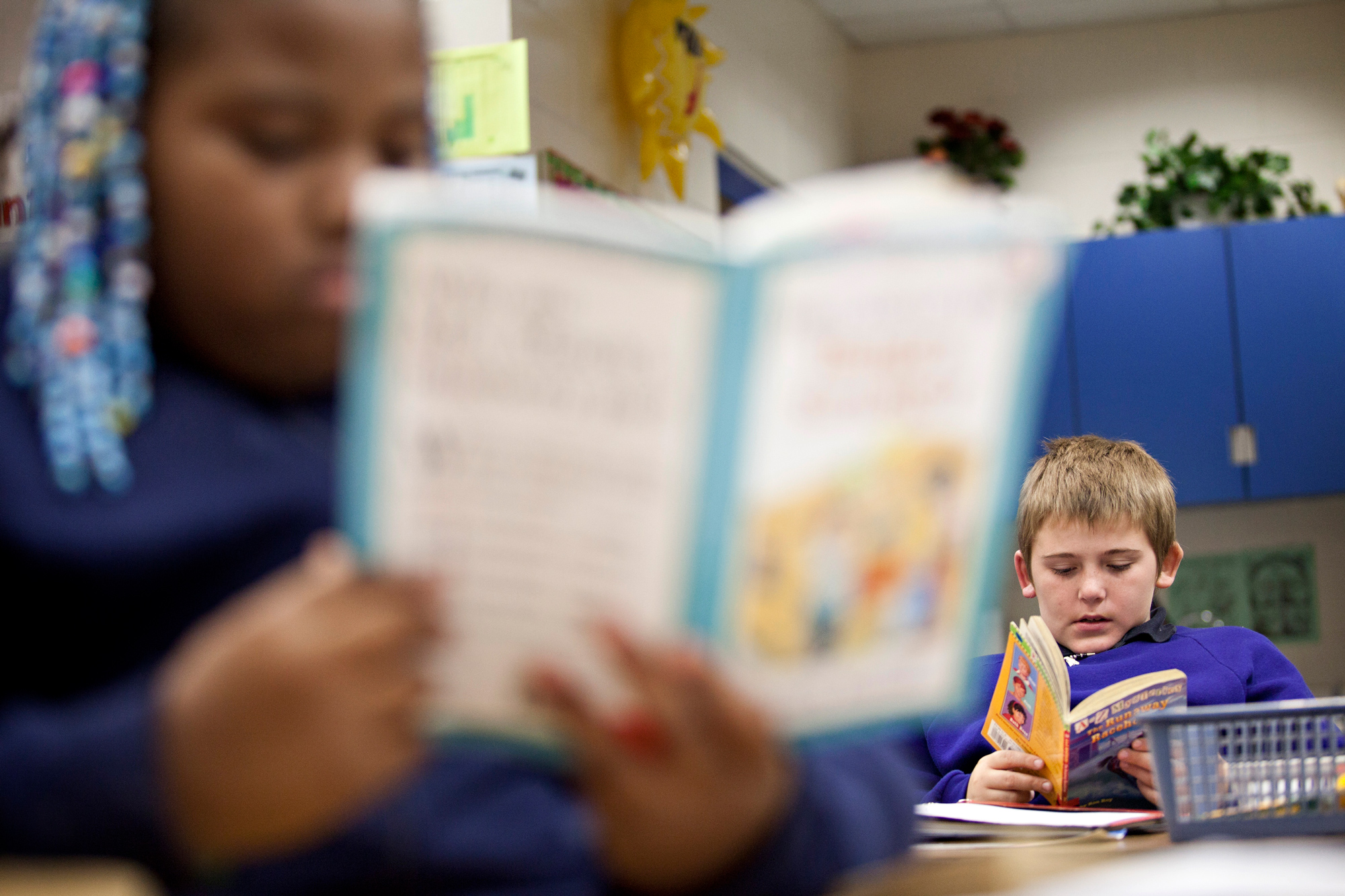 A boy reading and an out of focus girl reading.