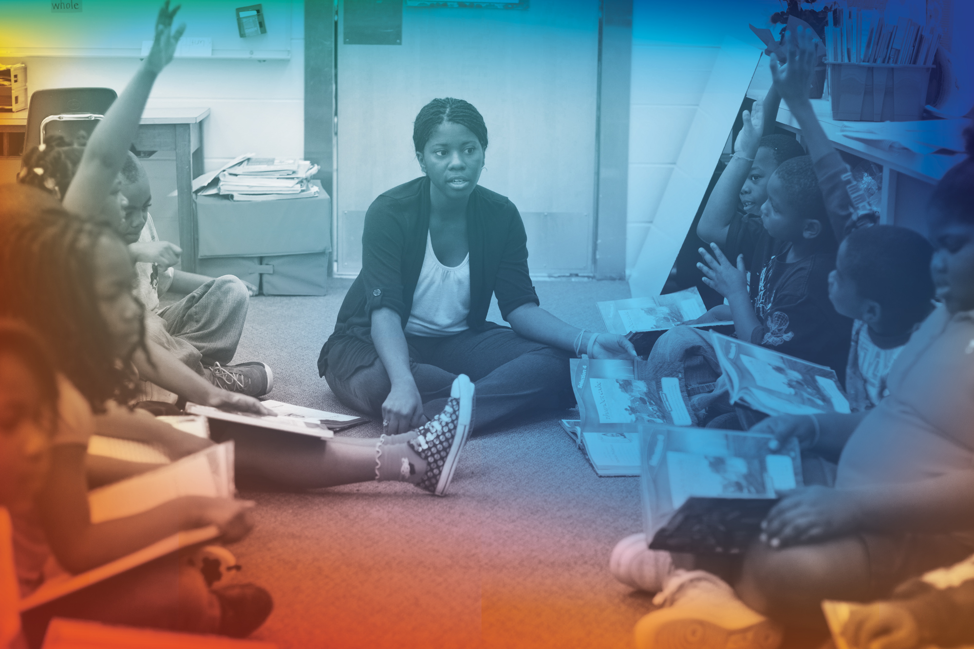 A teacher sitting on the floor with her young students.