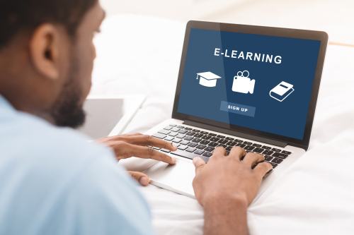 Man sitting with a laptop with a screen that says "E-Learning". 