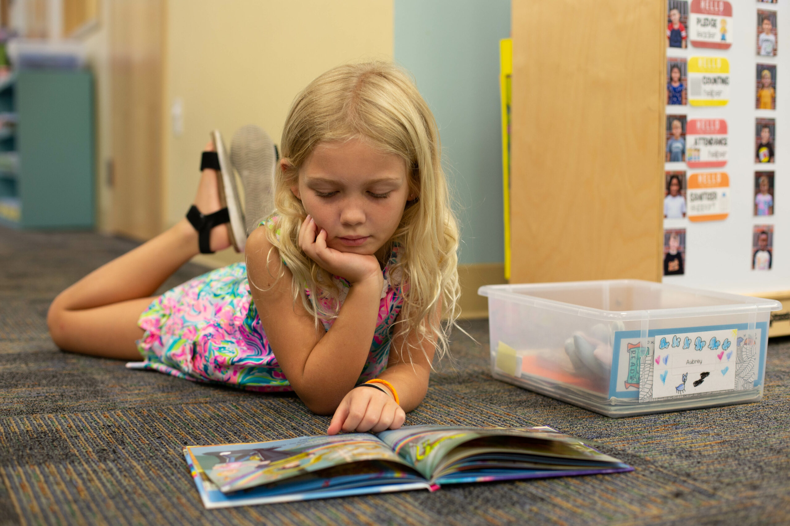 Young girl reads a book while laying on the floor