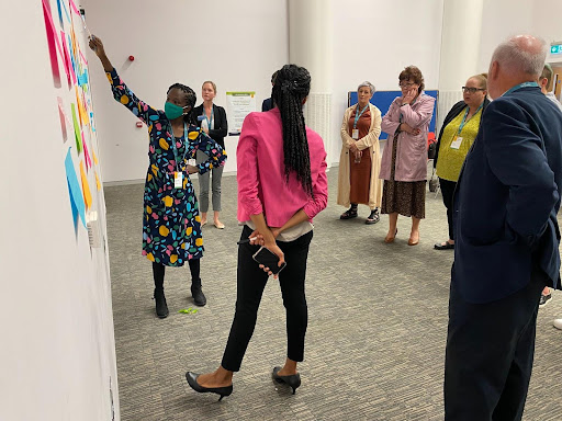 LfPL attendees gather in a small group and post their ideas on a collaborative wall using sticky notes.