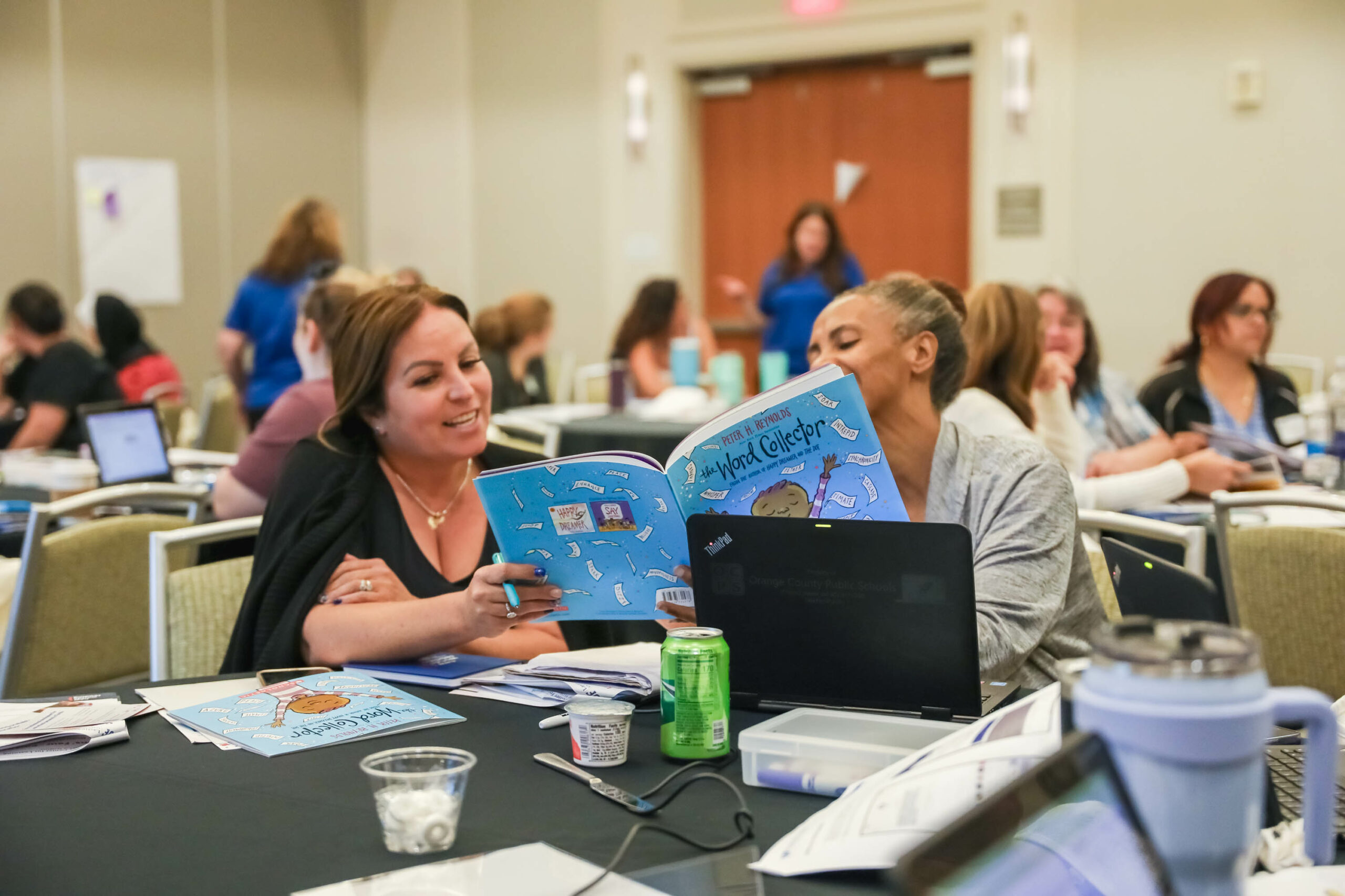 Two teachers read a New Worlds Reading book together and practice what they've learned in the session.