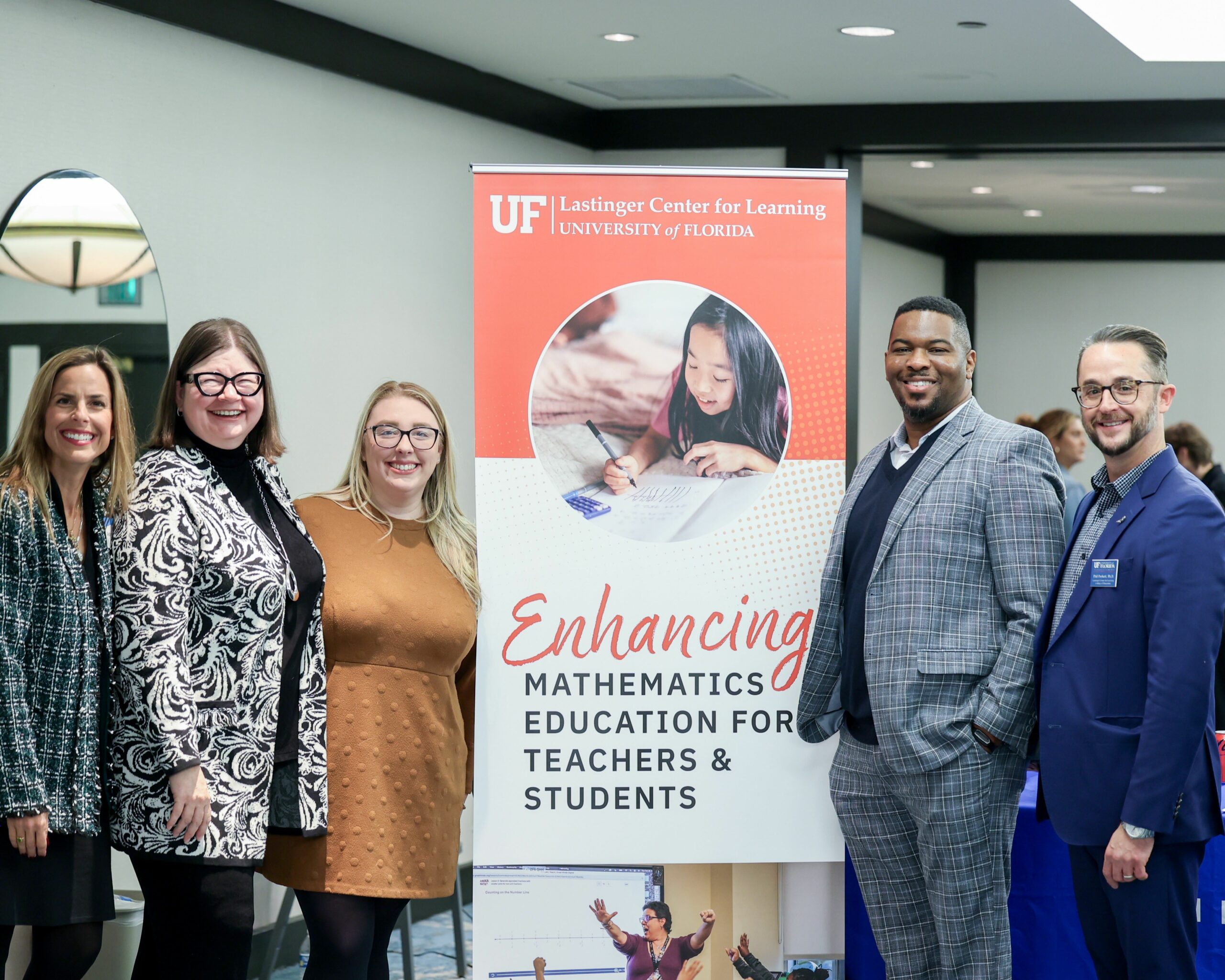 A photo of attendees of the Math Summit posing for a group photo in front of a standing banner at the summit's location.