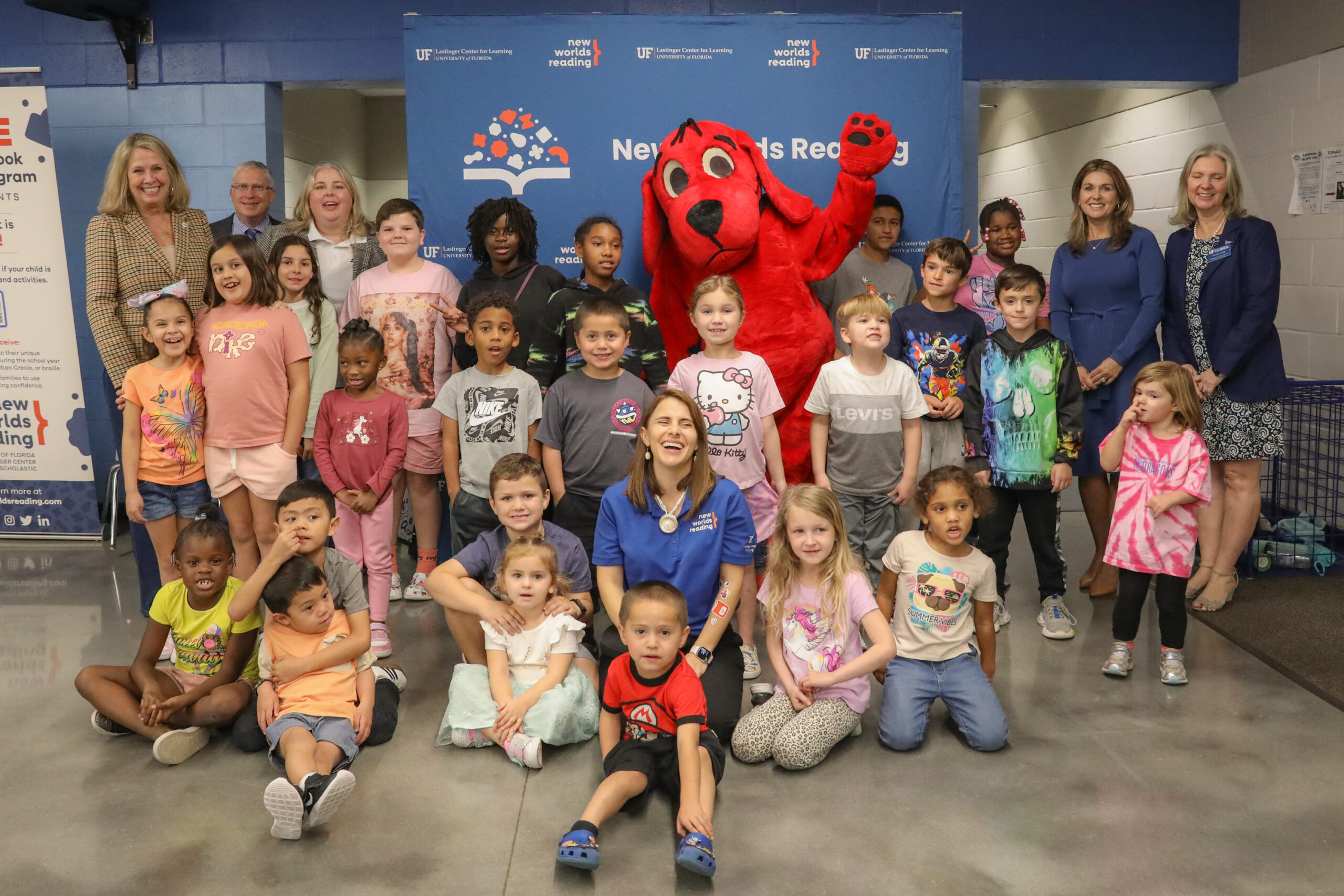 A group photo of children, donors, read aloud staff, and Clifford the Big Red Dog at a New Worlds Reading public family event. 